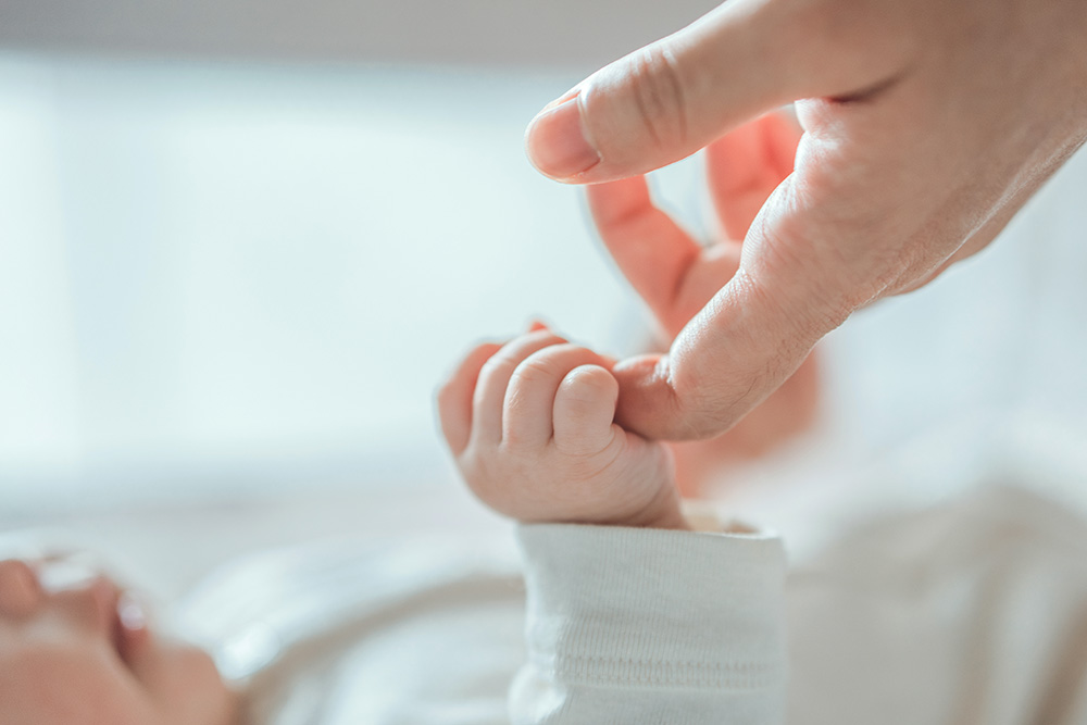 Baby holding mom's finger