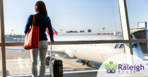 A woman stands in an airport looking through the window at the plane she is about to board. 