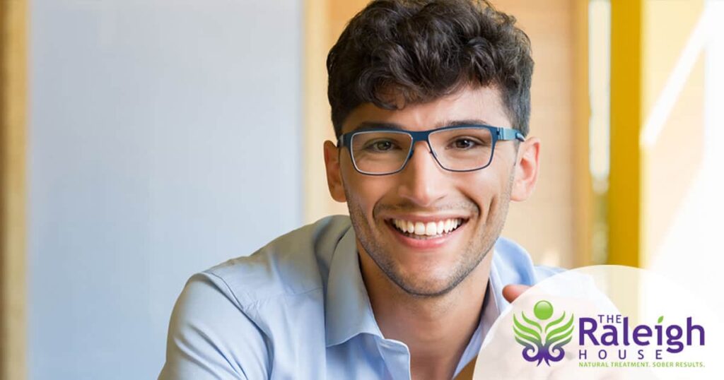 A happy young man smiles at the camera. 