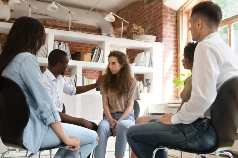 A woman being comforted during a group therapy session in addiction treatment.