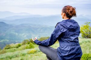 A woman practicing meditation in the mountains.
