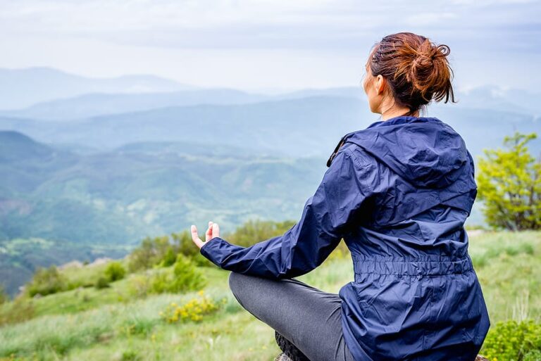 A woman practicing meditation in the mountains.