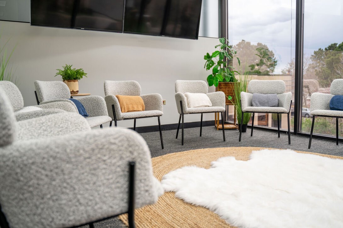 Group meeting area with white chairs and large TV screens