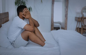 A man having a hard time getting out of bed, struggling with either depression or anxiety symptoms.
