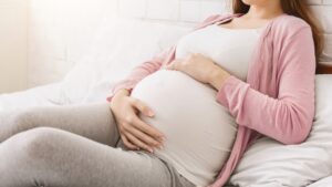Young millennial pregnant woman lying in bed