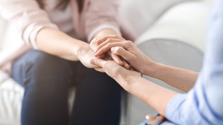 One woman offers comfort and reassurance by holding another woman hand during a heartfelt conversation