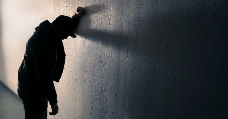 Intoxicated man against wall in dark alley